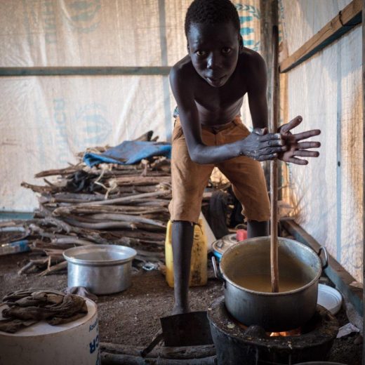 Flüchtlingsjunge aus dem Südsudan bereitet Maisbrei zu (Credit: Aktion Deutschland Hilft /Roland Brockmann)